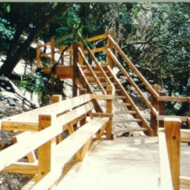 Wooden stairs and walkway with a bench in Fred Hollows Reserve